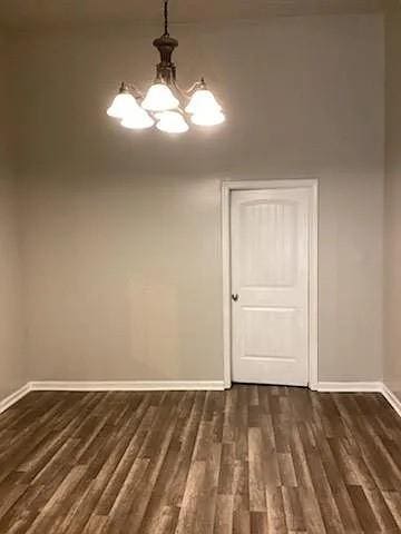 unfurnished dining area featuring dark hardwood / wood-style flooring and an inviting chandelier