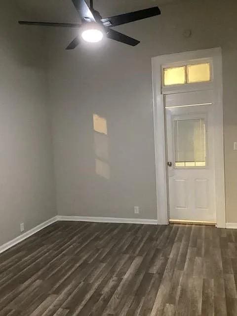 empty room with ceiling fan and dark hardwood / wood-style flooring