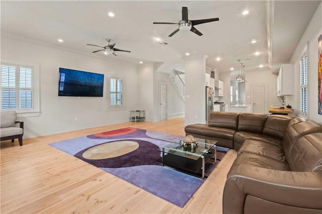 living room featuring ceiling fan, light hardwood / wood-style flooring, plenty of natural light, and ornamental molding