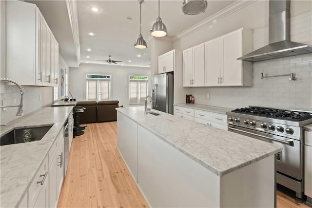 kitchen with white cabinets, wall chimney exhaust hood, a kitchen island, stainless steel appliances, and ceiling fan