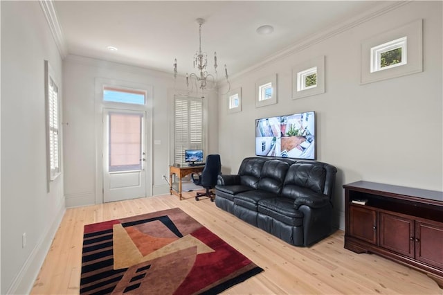 living room featuring light wood-type flooring, ornamental molding, a notable chandelier, and a wealth of natural light