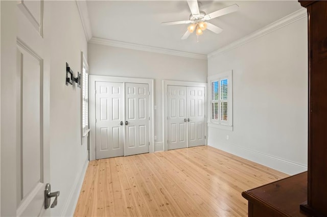 unfurnished bedroom featuring light hardwood / wood-style flooring, two closets, ceiling fan, and ornamental molding