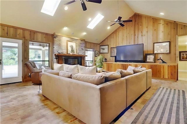 living room with wooden walls, a skylight, and ceiling fan