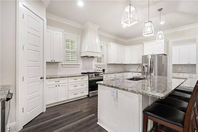 kitchen with white cabinets, a center island with sink, stainless steel appliances, and sink