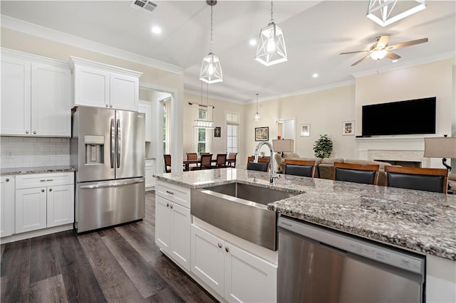 kitchen with sink, white cabinetry, a fireplace, stainless steel appliances, and ceiling fan