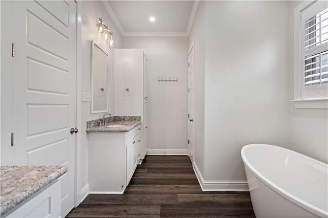 bathroom with ornamental molding, wood-type flooring, a bath, and vanity