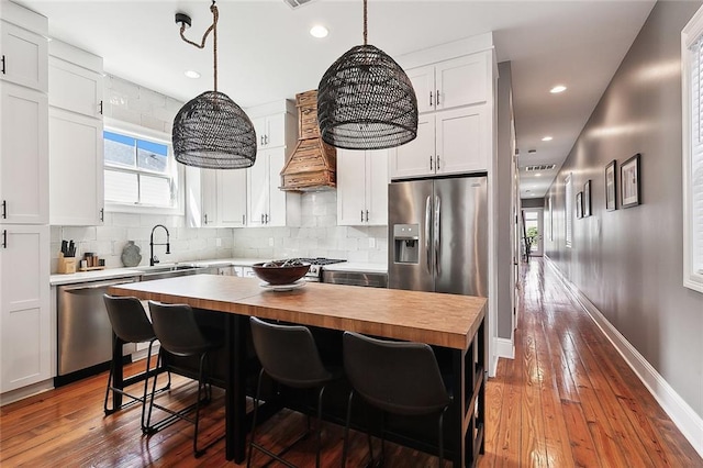 kitchen with white cabinetry, wood counters, custom exhaust hood, and stainless steel appliances