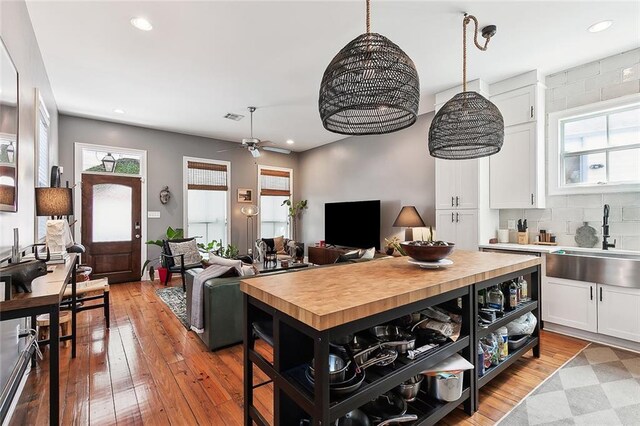 kitchen with tasteful backsplash, sink, light hardwood / wood-style flooring, and white cabinets