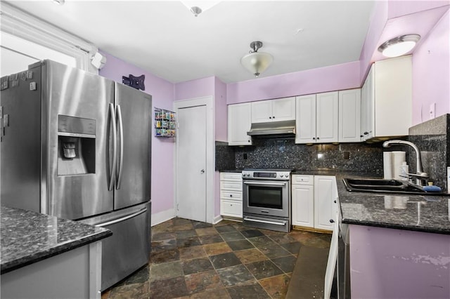 kitchen with decorative backsplash, dark stone countertops, white cabinetry, stainless steel appliances, and sink