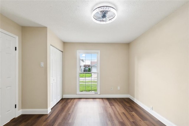 spare room with a textured ceiling, ceiling fan, and dark hardwood / wood-style flooring