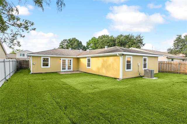 rear view of property featuring french doors, a yard, and central air condition unit