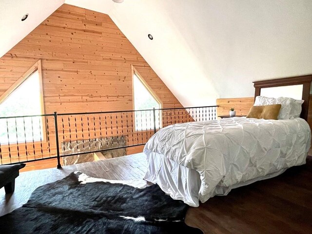 bedroom featuring wood-type flooring, vaulted ceiling, wood walls, and a mail area