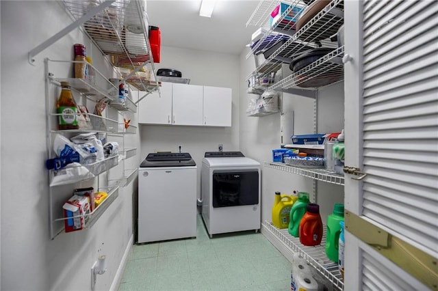 clothes washing area featuring cabinets and washer and dryer