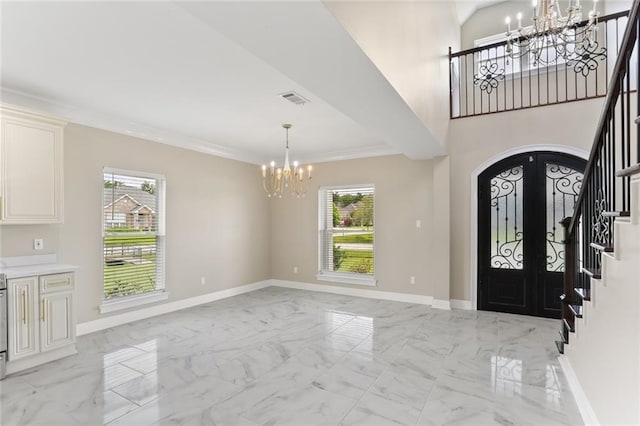 foyer entrance featuring ornamental molding, a wealth of natural light, and french doors