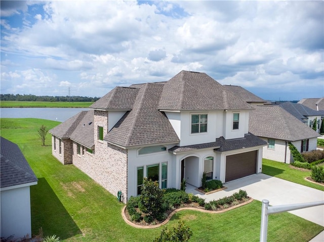 view of front of home with a garage, a water view, and a front lawn