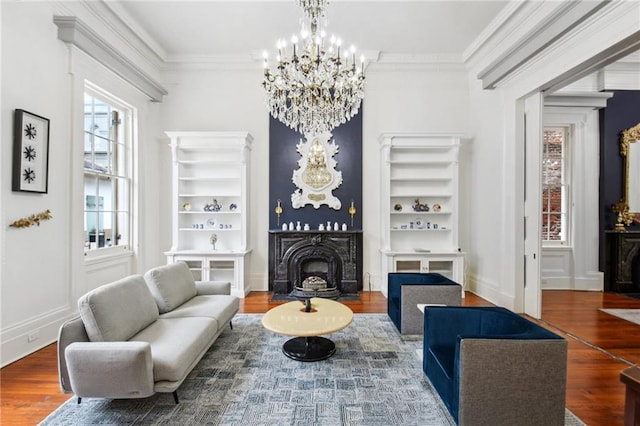 living room with built in shelves, ornamental molding, a notable chandelier, and hardwood / wood-style floors