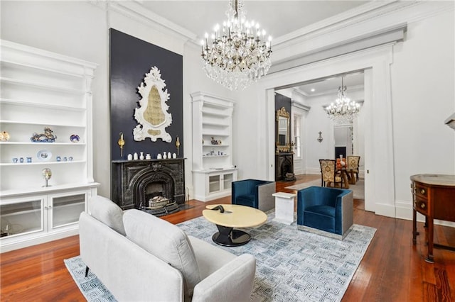 living room with a notable chandelier, built in features, ornamental molding, and dark hardwood / wood-style flooring