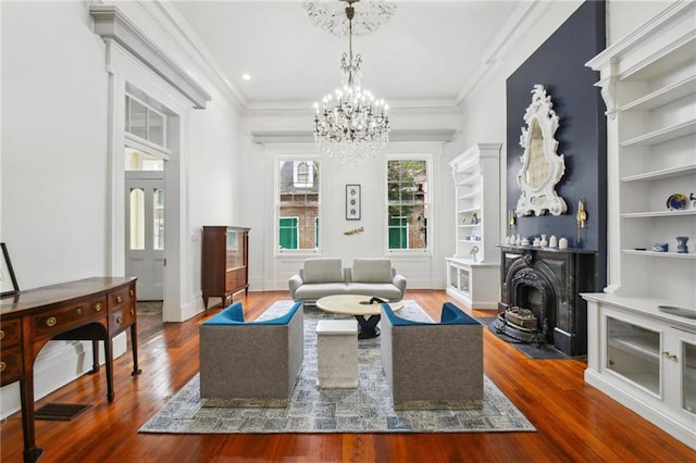 living room with an inviting chandelier, built in features, hardwood / wood-style floors, and crown molding