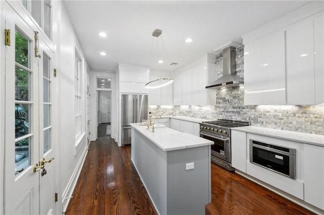 kitchen featuring hanging light fixtures, wall chimney exhaust hood, white cabinetry, appliances with stainless steel finishes, and dark hardwood / wood-style floors