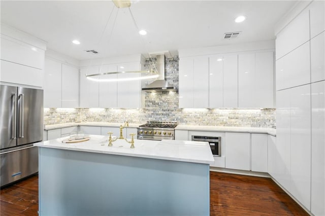 kitchen with wall chimney exhaust hood, white cabinetry, appliances with stainless steel finishes, and dark hardwood / wood-style floors