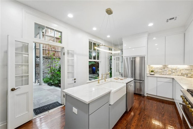 kitchen featuring hanging light fixtures, white cabinetry, dark hardwood / wood-style flooring, high quality appliances, and a kitchen island with sink