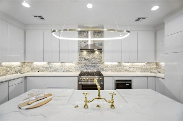 kitchen featuring light stone counters, white cabinets, stainless steel appliances, and tasteful backsplash