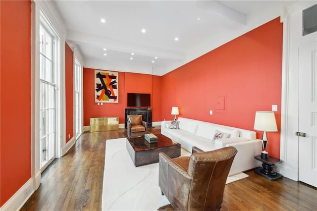 living room featuring beamed ceiling and dark wood-type flooring