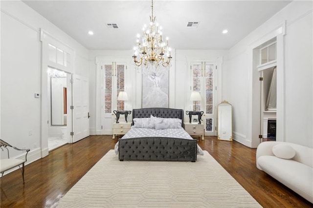 bedroom with wood-type flooring, a notable chandelier, and connected bathroom