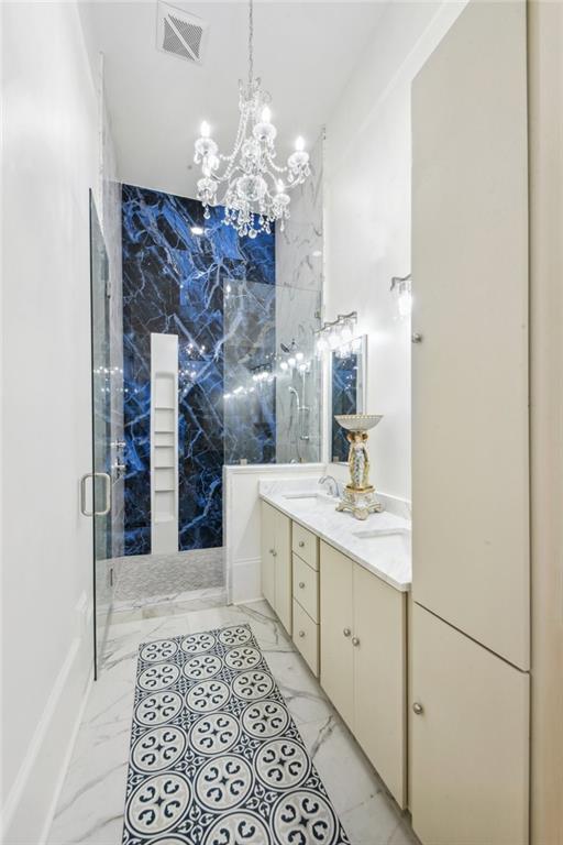 bathroom featuring tile walls, vanity, a chandelier, and a shower with door