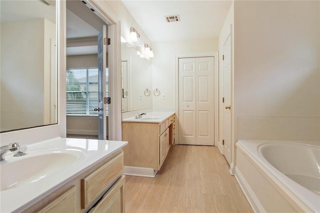 bathroom featuring wood-type flooring, vanity, and a bathtub