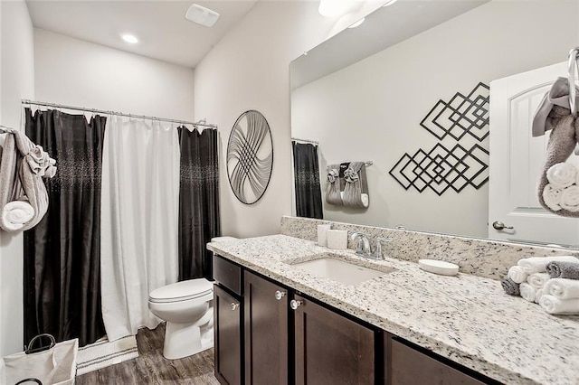 bathroom with a shower with shower curtain, hardwood / wood-style flooring, vanity, and toilet