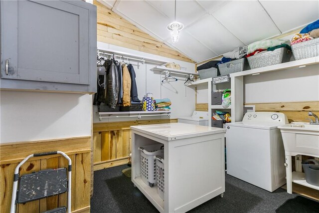 laundry area with washing machine and clothes dryer, wooden walls, dark carpet, and cabinets