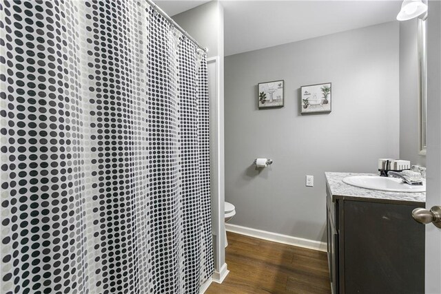 bathroom with wood-type flooring, a shower with curtain, vanity, and toilet