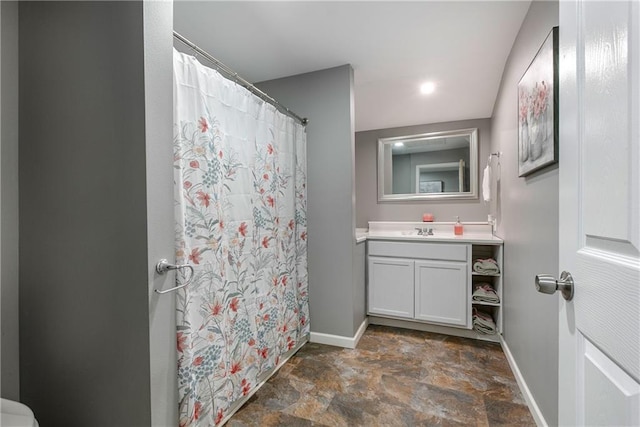 full bath featuring stone finish floor, vanity, a shower with shower curtain, and baseboards