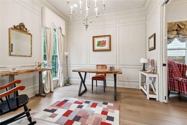 misc room with light wood-type flooring, an inviting chandelier, a wealth of natural light, and ornamental molding