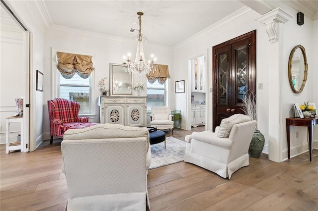 living room featuring light hardwood / wood-style flooring, a chandelier, and ornamental molding