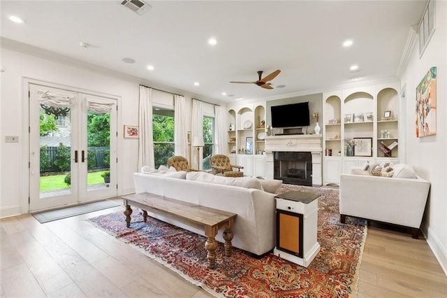 living room featuring ceiling fan, plenty of natural light, built in features, and a fireplace