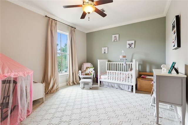 carpeted bedroom featuring ceiling fan, crown molding, and a nursery area