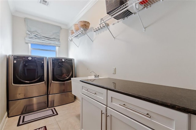 laundry area featuring washing machine and clothes dryer, crown molding, light tile patterned floors, and cabinets