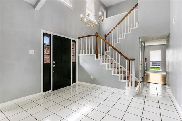 tiled foyer featuring a high ceiling and a chandelier