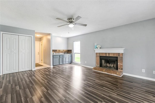 unfurnished living room with ceiling fan, dark hardwood / wood-style floors, a fireplace, and a textured ceiling