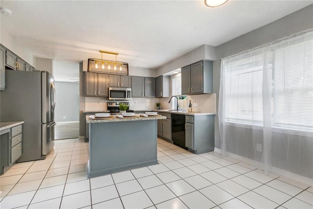 kitchen with hanging light fixtures, sink, backsplash, appliances with stainless steel finishes, and a center island