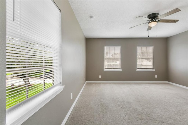 carpeted empty room with a textured ceiling, ceiling fan, and plenty of natural light