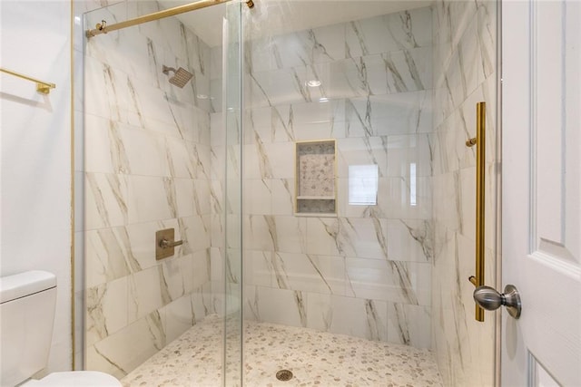 bathroom featuring a shower with shower door and toilet