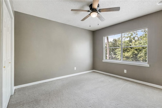 carpeted spare room featuring ceiling fan and a textured ceiling