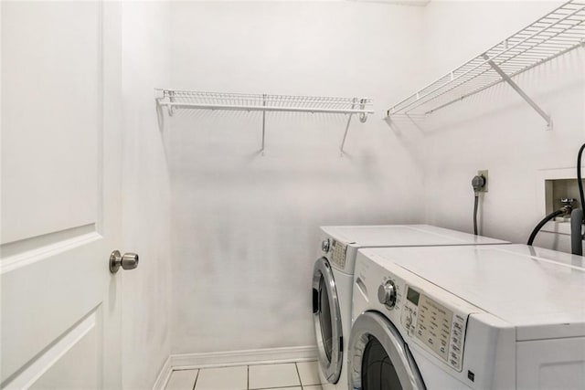 clothes washing area featuring light tile patterned floors and washing machine and clothes dryer