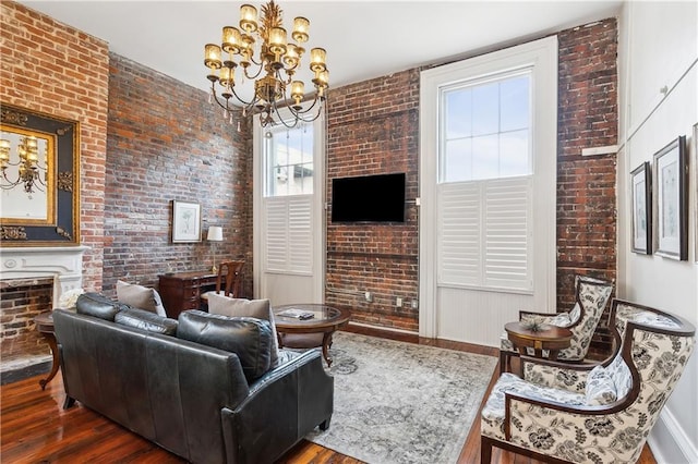 living room with a chandelier, brick wall, and dark wood-type flooring