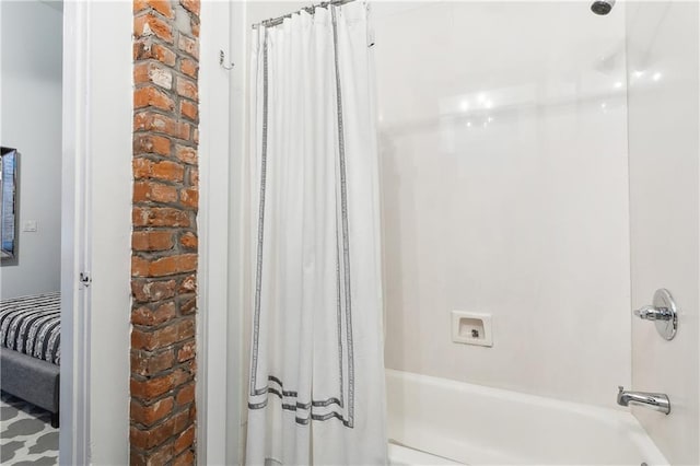 bathroom with brick wall and shower / bath combo