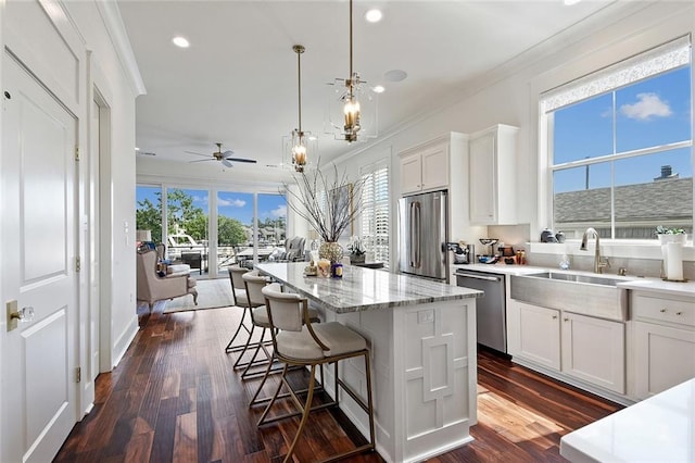 kitchen with stainless steel appliances, hanging light fixtures, white cabinetry, and a center island