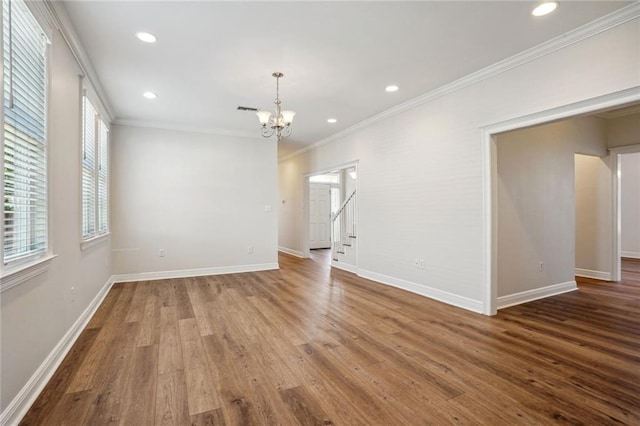 spare room with crown molding, a chandelier, and wood-type flooring